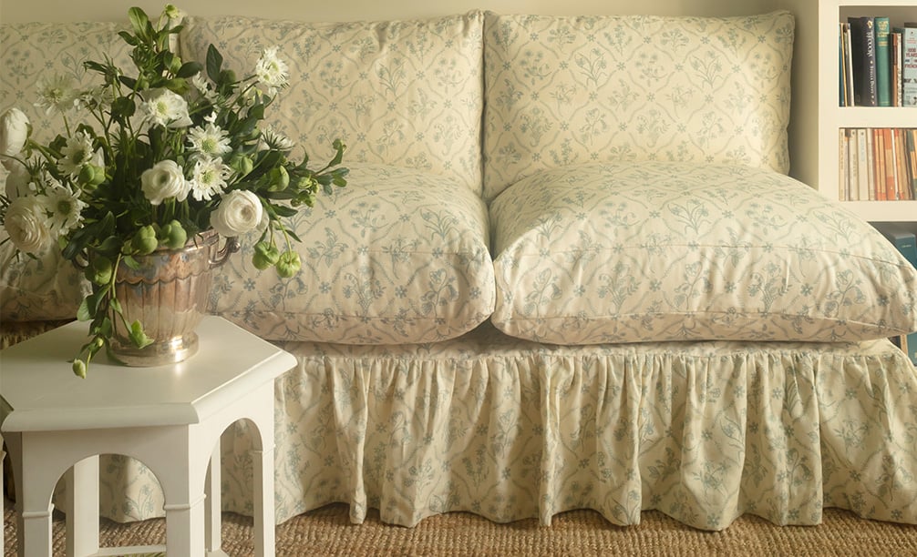 Lucknawi Flower Blue on a sofa behind  small white hexagonal table and flowers