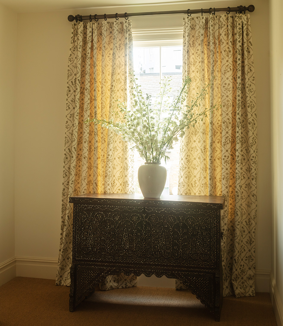Lucknawi Flower Moss long curtains behind an antique chest with a large vase of flowers