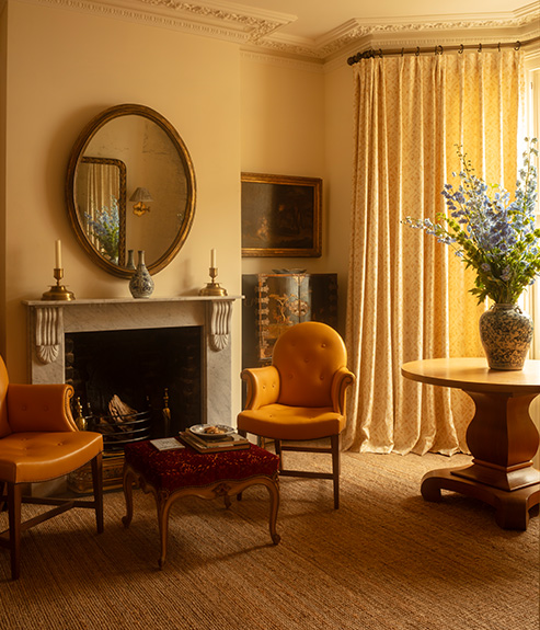 Lucknawi Flower Straw large curtains behind a round table and yellow leather armchair