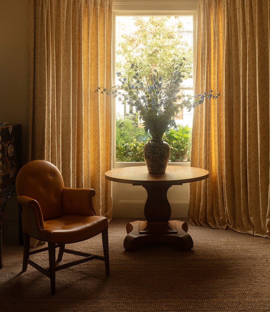 Lucknawi Flower Straw large curtains behind a round table and yellow leather armchair