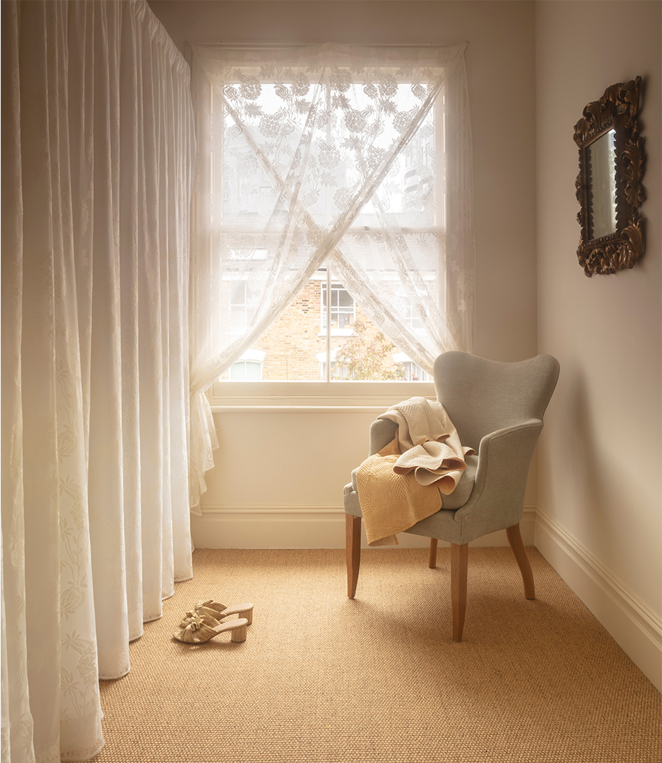 Mole Celadon upholstered armchair in front of a lace curtain 