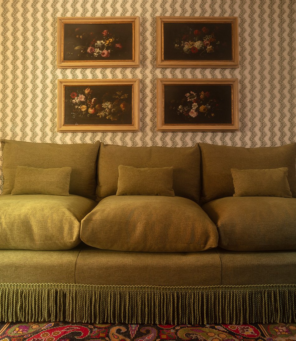 Mole Moss fabric upholstered on a sofa with striped wallpaper and four oil painting of flowers