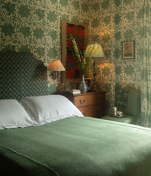 Palampore Blossom Emerald wallpaper in a bedroom with a green bed