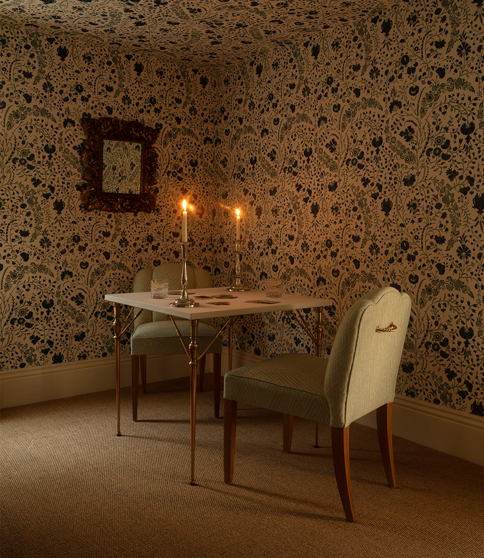 Philae Duck Egg Blue upholstered on two chair around a card table with candles and blue and white floral wallpaper
