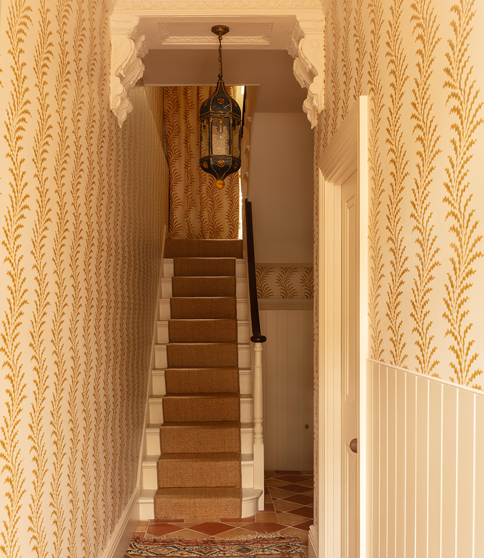 Scrolling Fern Frond wallpaper in a hallway with a large hanging antique light