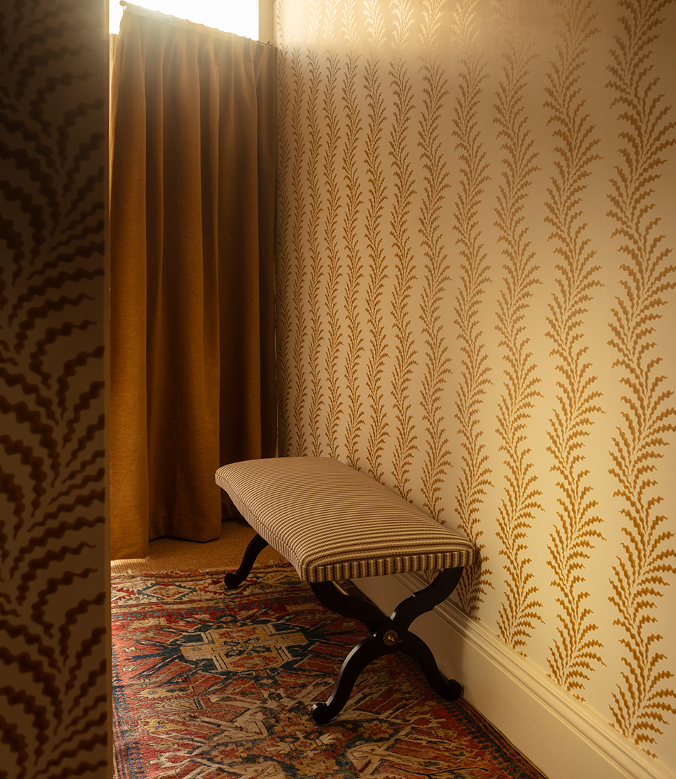 Scrolling Fern Frond wallpaper in a hallway with a brown and white striped bench 