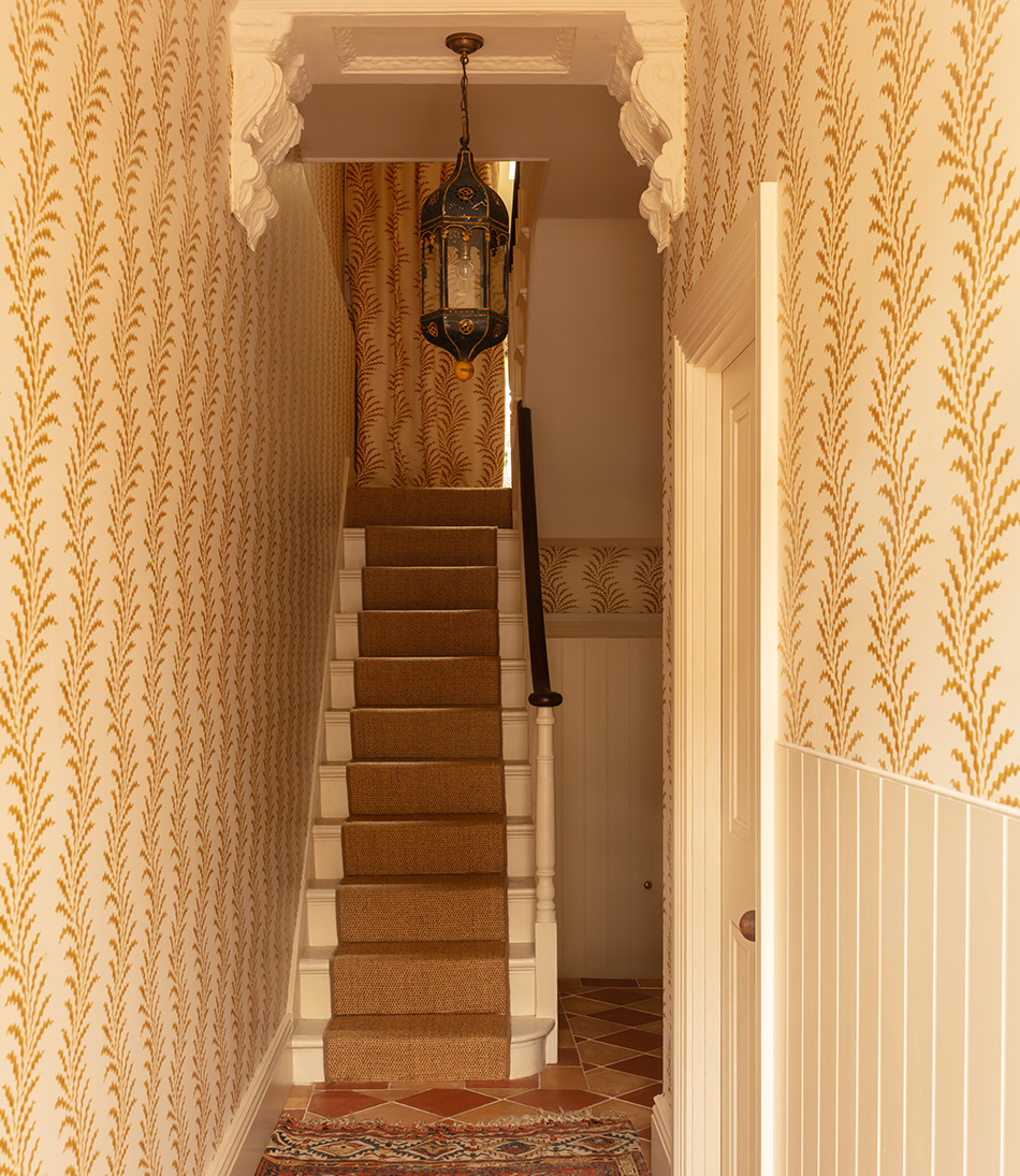 Scrolling Fern Frond wallpaper in a hallway leading to the stairs 