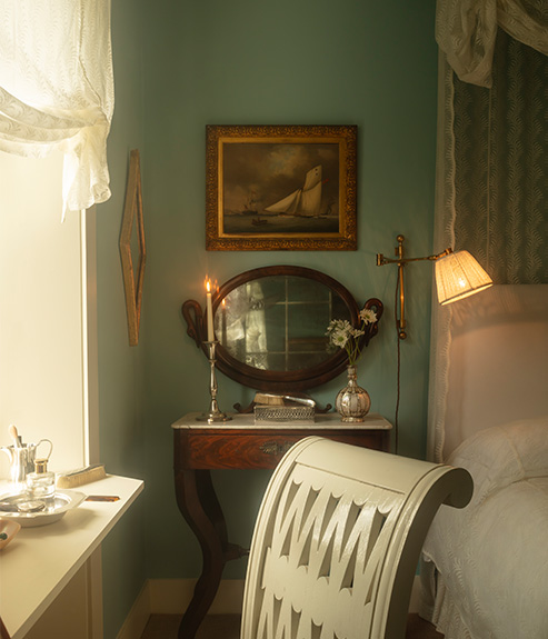 Scrolling Fern Silhouette Lace as a bed curtain and bed cover with wooden bedside tables and brass wall lights