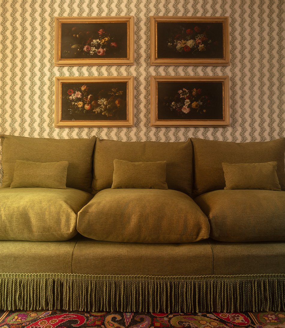 Scrolling Fern Silhouette Moss behind a green sofa and four oil paintings