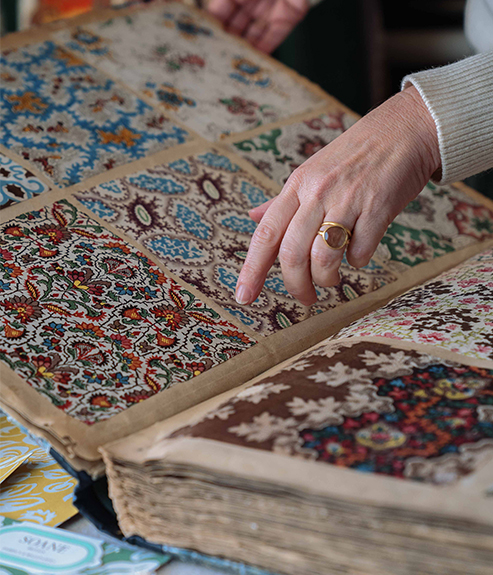 Hands pointing at fabric swatches in book