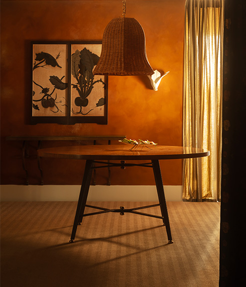 The Rattan Big Bad Kitty hanging light above a timber and leather dining table