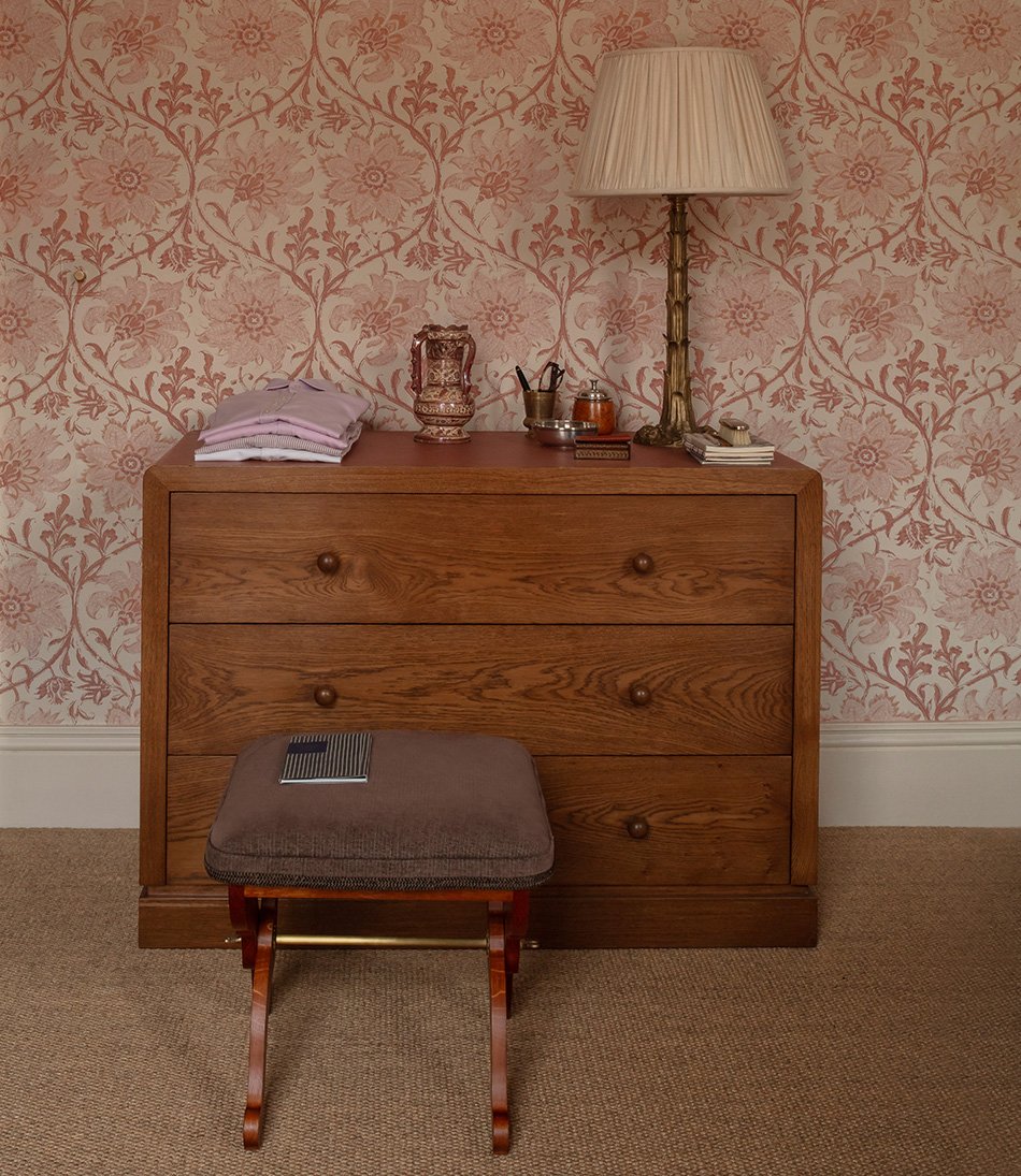 The Templeton Chest in a pink floral bedroom with a brass lamp