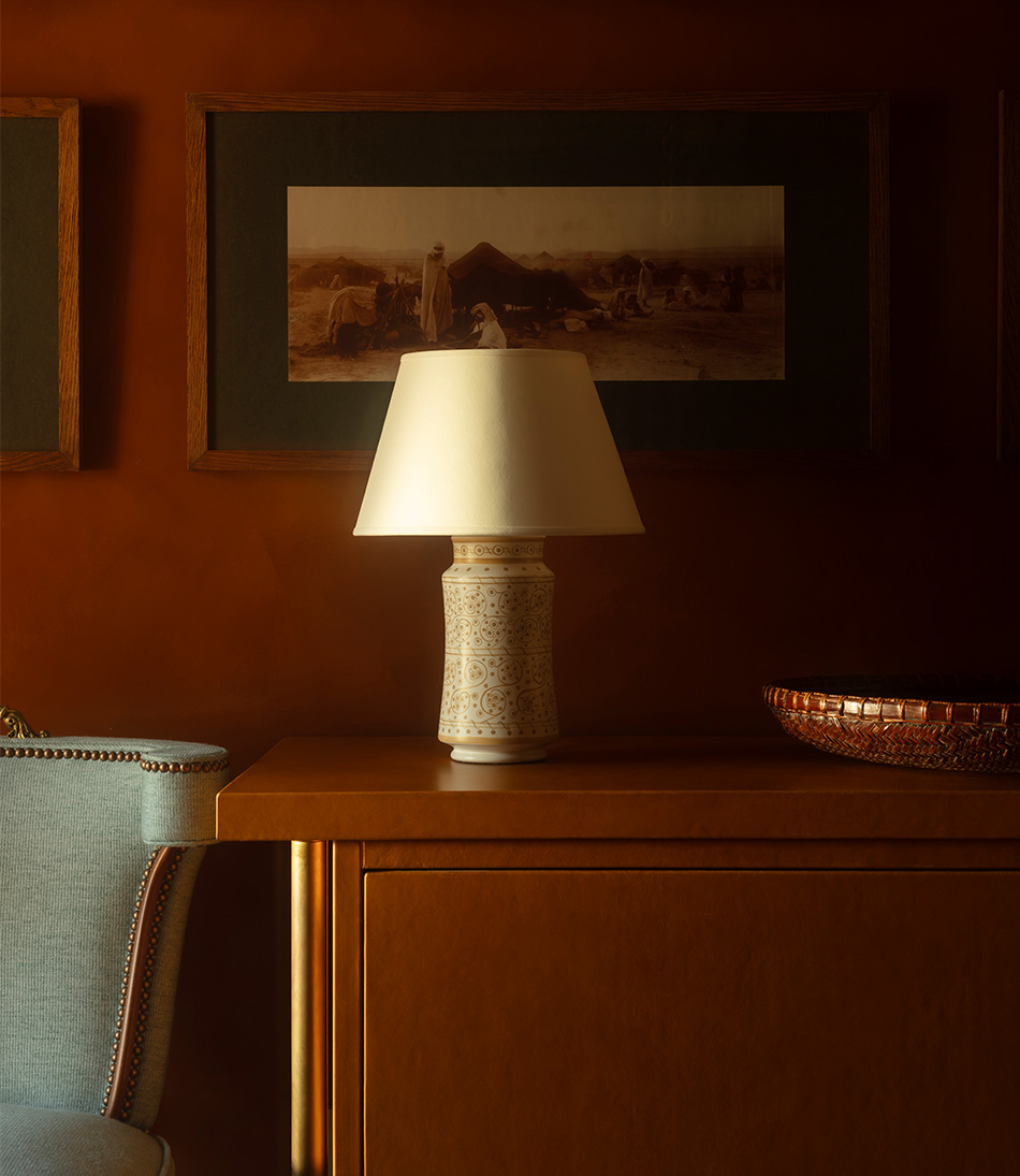 The Apothecary Lamp Viburnum is a small gold and ivory timber lamp on a orange leather cabinet and a blue chair 