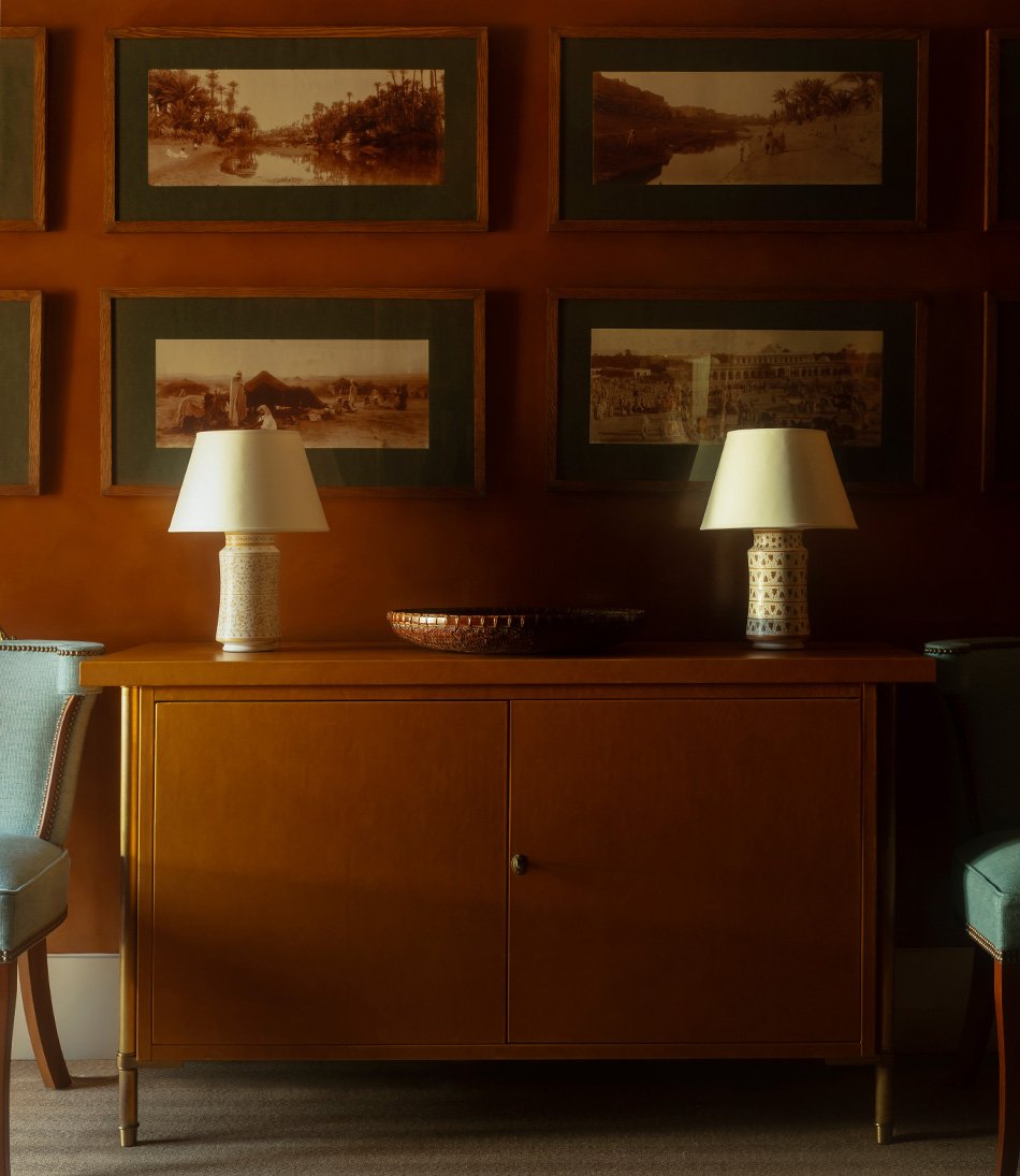 The Apothecary Lamp Viburnum is a small gold and ivory timber lamp on a orange leather cabinet and a blue chair 