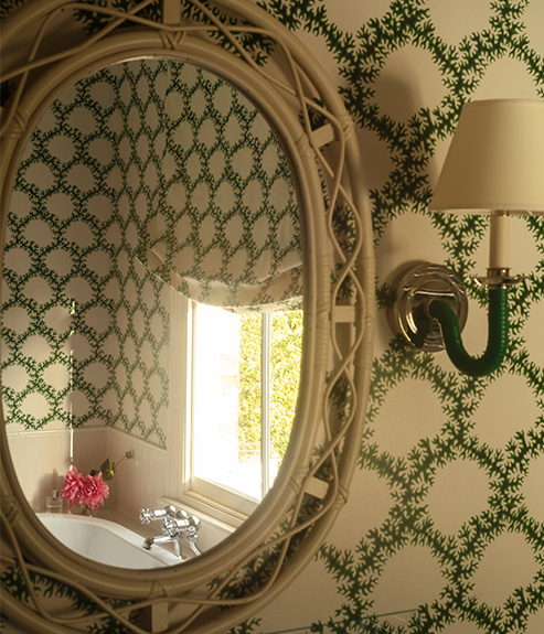 The Card Shade 7" for osh bulb on a rattan wall light in a green bathroom with a white lacy mirror