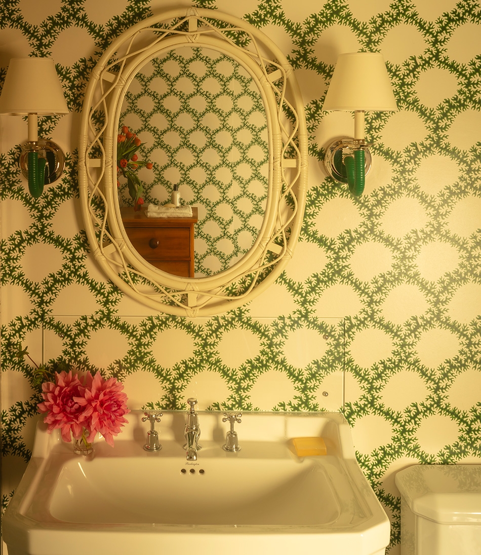 The Card Shade 7" for osh bulb on a rattan wall light in a green bathroom with a white lacy mirror