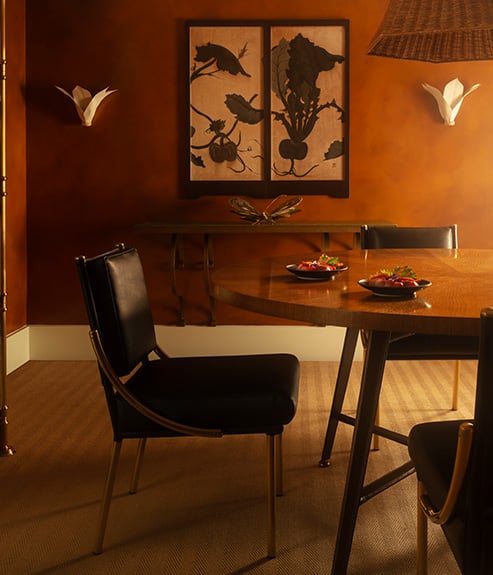 The Gambado Table with a leather chair and artwork on the wall behind