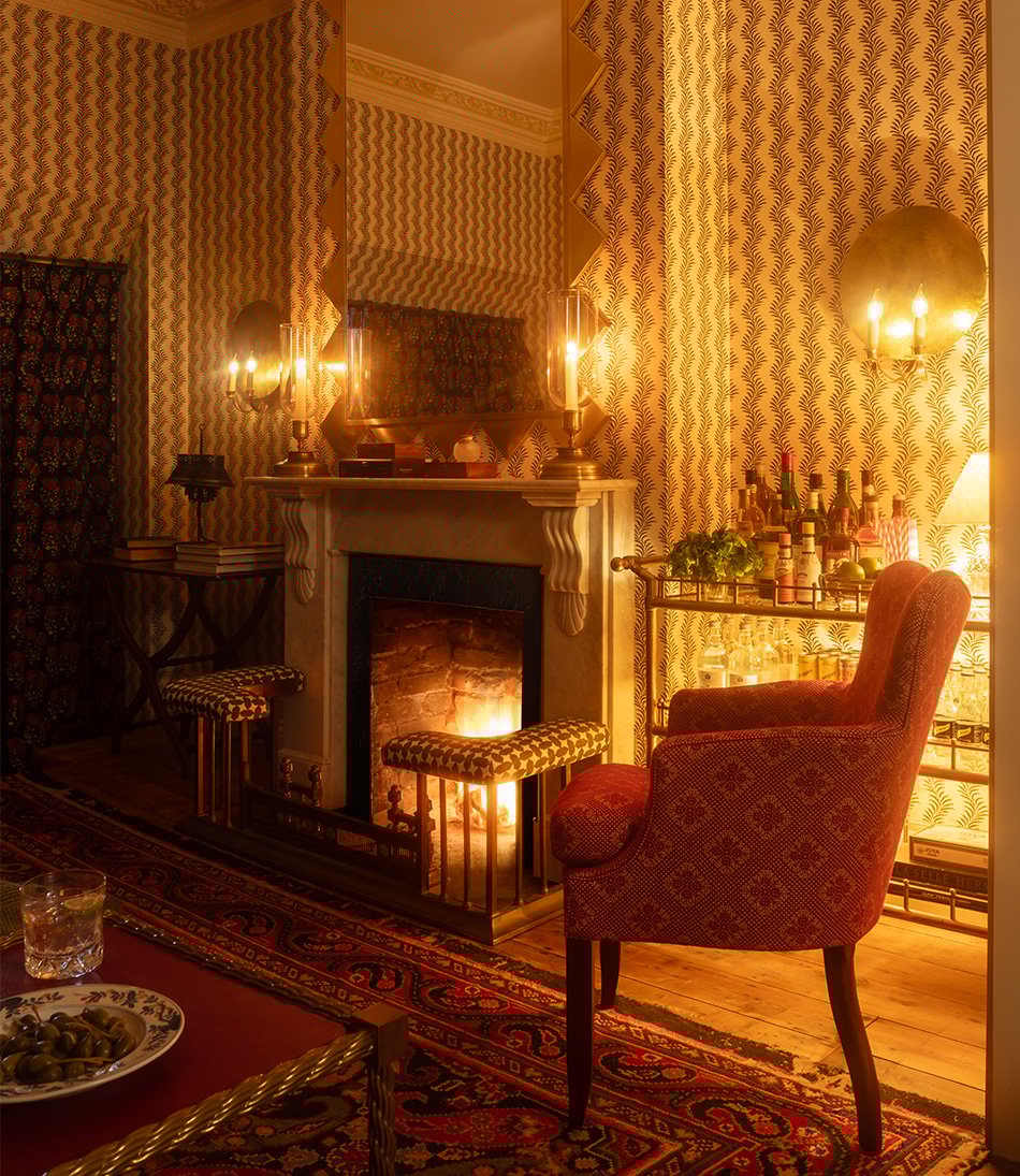 The Gigi chair with striped wallpaper and a fireplace