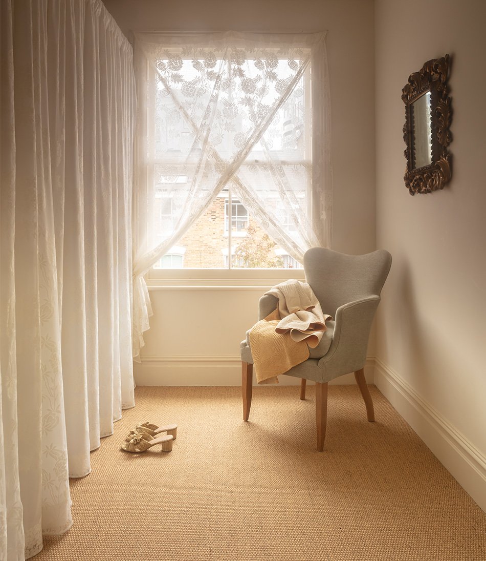The Gigi chair in a pale blue fabric and shown with a lace curtain 