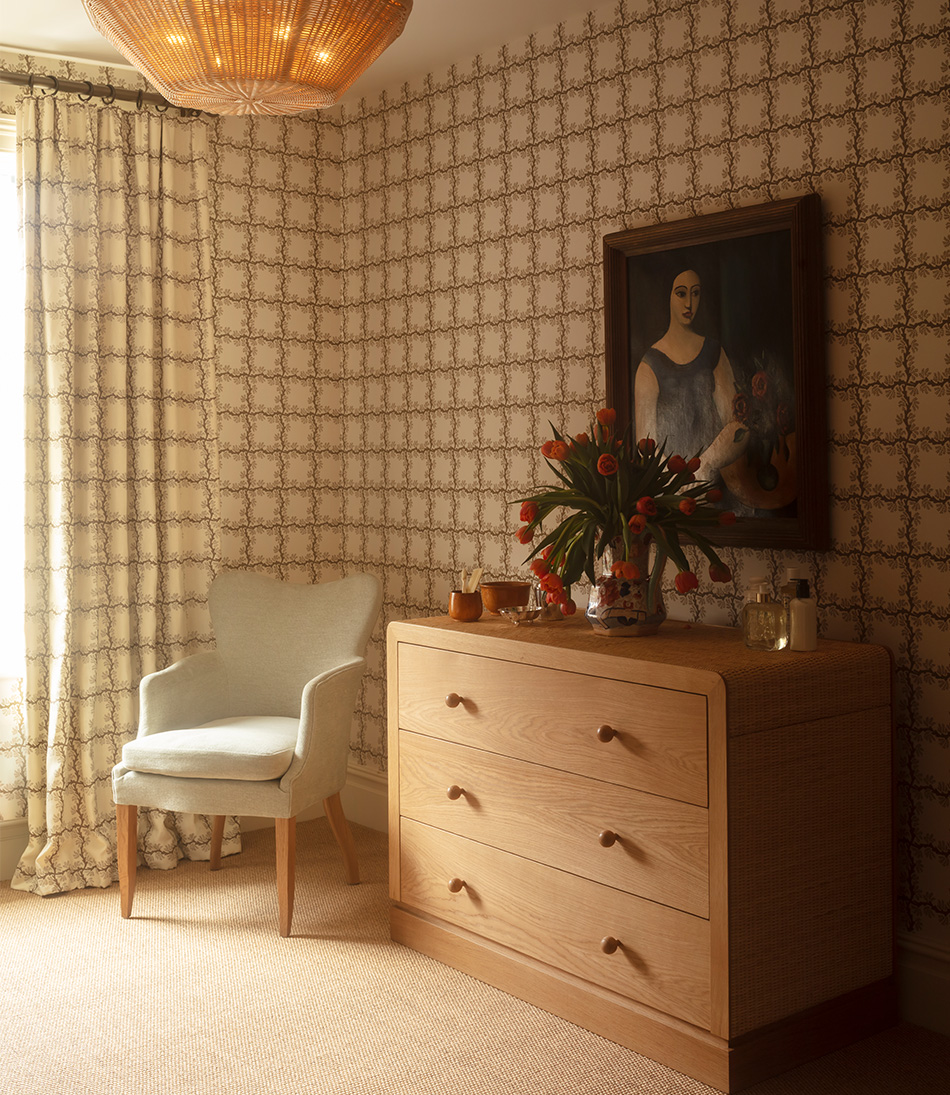 The Rattan Templeton Chest with pale blue armchair and geometric brown wallpaper 