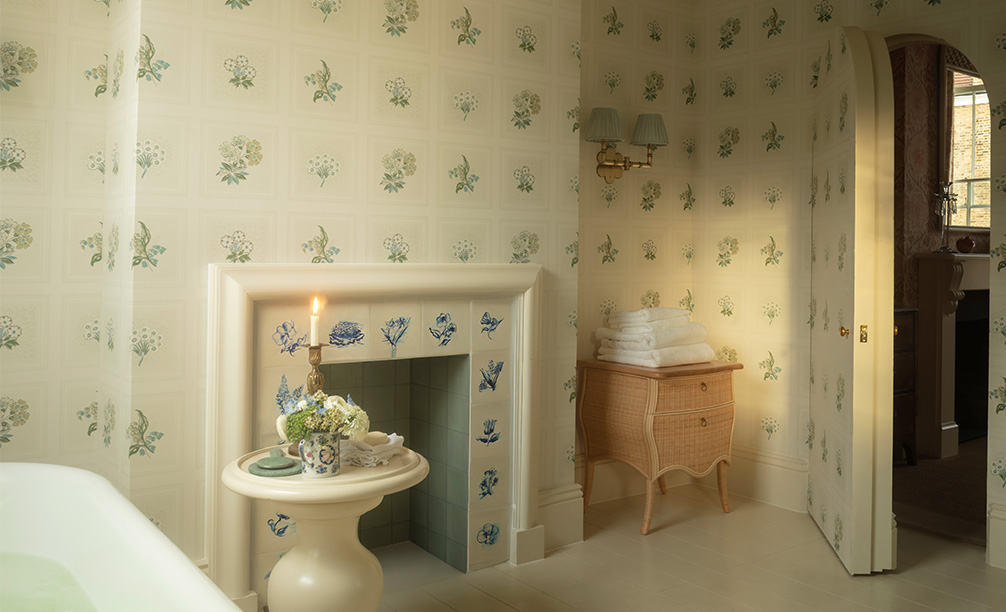 The Virginia Chest in natural rattan, in a blue and white bathroom with a brass double wall light with blue shades 